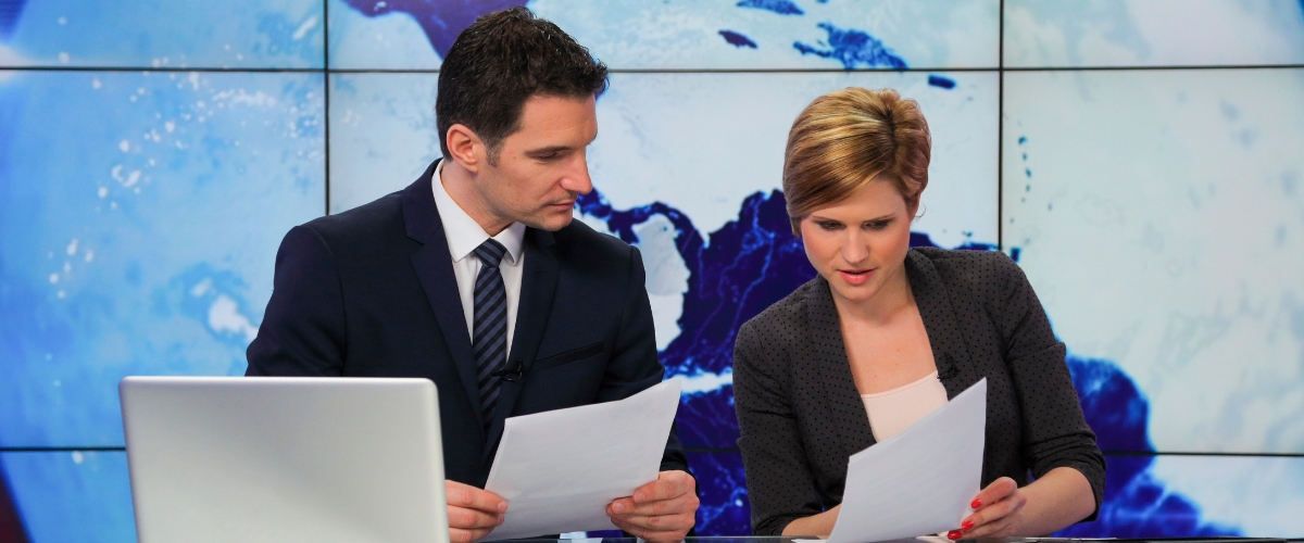 two people looking at notes on a newscast